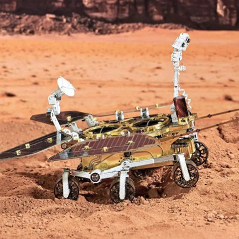 Space Rover 281+ Piece STEM Mechanical Explorer Puzzle Kit For Adults And Gearheads, DIY Aerospace Model For Home Desk Display, Educational Building Project Gift With Realistic Wheels, Antennas, And Discovery Detail. Metal space rover model on sandy terrain with wheels, antennas, and solar panels