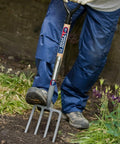 Person using a Heavy Duty Digging Fork With Forged Carbon Steel Tines For Tough Soil Aeration And Cultivation in a garden.