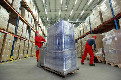 Workers handle pallets wrapped in Industrial Strength 18 Inch Stretch Film Wrap Roll Set For Moving And Packing in warehouse.