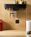 Slick Black Plastic Wall Access Panel Swings Open For Easy Inspections fits neatly below a modern sink in a bathroom setting.