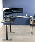 Rock Solid Corner Standing Desk Rig In Matte Black With Lightning Fast Height Adjustments And Split Tabletop Design showcasing dual monitors and laptop.