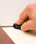 Hand using Adjustable Precision Scribe Tool With Eight Incremental Offsets for precise marking near baseboard corners.
