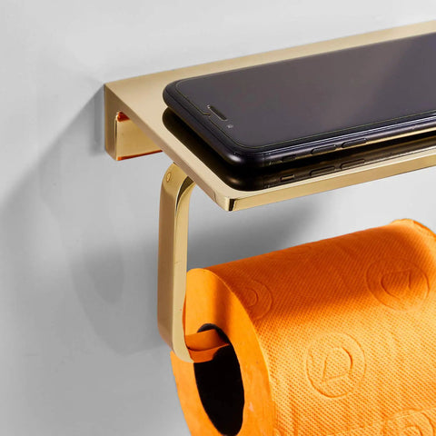 Solid Brass Toilet Paper Holder With Gold Finish, Hotel Style Tissue Roll Holder Plus Built In Cell Phone Shelf, Rust Resistant Chrome Finish, Pro Grade Heavy Duty Bathroom Organizer For Rolls Up To 5.31 Inches with black phone on shelf