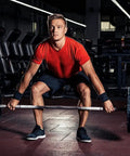 Man lifting weights in gym wearing a red shirt, highlighting strength and fitness focus