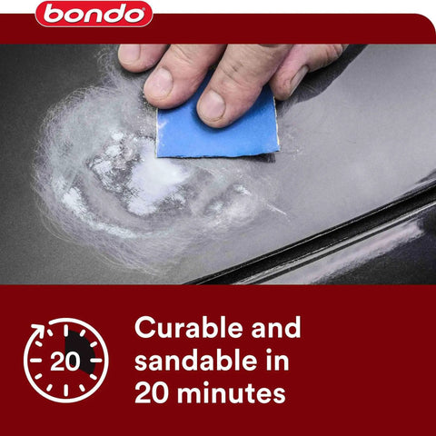 Person applying nitrocellulose glazing putty on car body panel using a blue sanding pad.