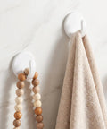 Eight Piece White Peel And Stick Wall Hooks Offer A Super Strong Hold That Skips The Drilling Headaches While Making Everyday Organizing Easy Peasy And Totally Damage Free For Any Room, displaying a towel and beads hanging.