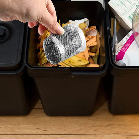 Hand holding a silver Hair Catcher for Shower-Self-Adhesive Drain Strainer Filter Roll above a compost bin filled with organic waste.