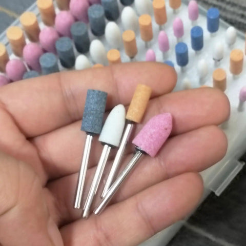 Hand holding Assorted 100 Piece Grinding Stones Set With One Eighth Inch Shank For Rotary Tools Aluminum Oxide Mounted Grinding Bits