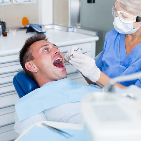 Dentist examining a patient's teeth while wearing face mask and gloves