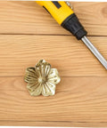 Vintage Brass Flower Cabinet Handle Single Hole Drawer Pull For Wardrobe And Cupboard Doors on wooden surface with screwdriver