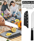 All In One Camping Kitchen Set With Stainless Steel Tongs Slotted Spatulas Spoons Chef Knife Kitchen Shears Bottle Opener Peeler And Spice Bottles Plus A Chopping Board And Four Plastic Plates For Outdoor Cooking On The Go Picnics And BBQ with chef knife shown cutting lemons on board.