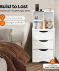 White vertical bedside cabinet with three drawers and open storage shelf beside bed, displaying books and decor items.