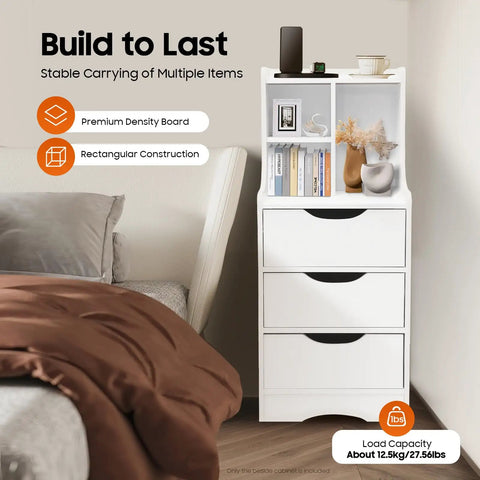 White vertical bedside cabinet with three drawers and open storage shelf beside bed, displaying books and decor items.