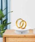 Spill Your Secrets With This Hype BESPORTBLE 360 Auto Rotating Display Stand showcasing two gold rings on a sleek velvet top.