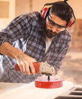 5.5-inch bi-metal hole saw, red, mounted on a drill in a workshop.