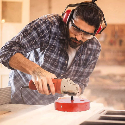 5.5-inch bi-metal hole saw, red, mounted on a drill in a workshop.