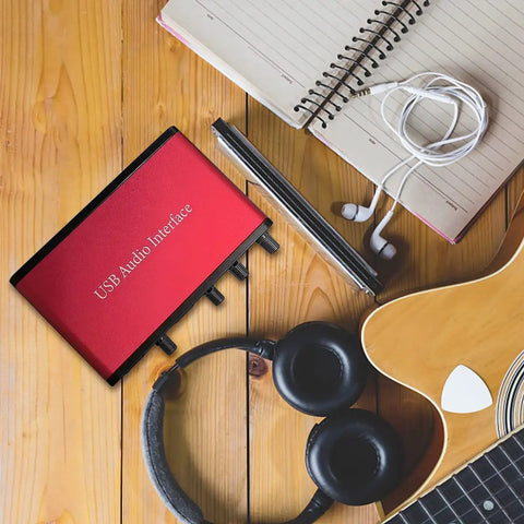 2x2 USB Audio Interface With 48V Phantom Power And 24-Bit 96kHz Recording next to headphones, notebook, smartphone, and guitar