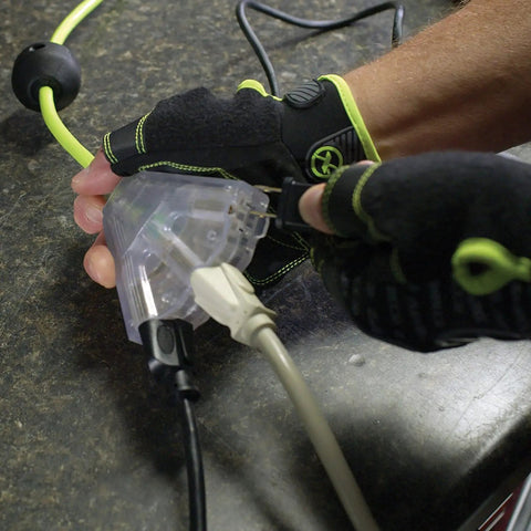 Gloved hand using Retractable 25 Ft Extension Cord Reel With 16/3 SJTOW Oil Resistant Cable, Lighted Triple Tap Outlet.