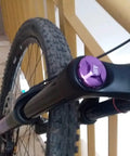 Close-up of CNC Aluminum Mountain Bike Fork Valve Cover Upgrade Front Fork Cap Protector in purple on MTB fork.