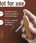 Ergonomic Wooden Needle Threader For Hand Sewing With Hardwood Handle And Stainless Steel Hook For No Fuss Easy Threading 1 Cm Extended Tip That Fits Small Eye Needles And Sewing Machines Savina being held by a hand.