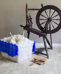 KeepBox 12 Gallon Stackable Storage Tote With Attached Lid For Easy Nesting Clear Plastic Box next to spinning wheel on carpet