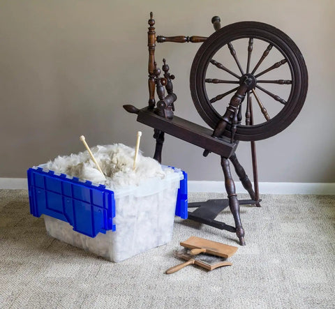 KeepBox 12 Gallon Stackable Storage Tote With Attached Lid For Easy Nesting Clear Plastic Box next to spinning wheel on carpet