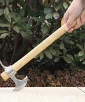 Person holding Stainless Steel Double Headed Pickaxe With Wood Handle And Comfort Grip For Easy Digging in a garden setting