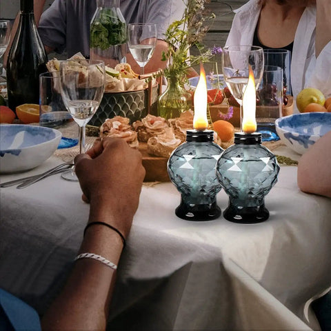 Four Pack Glass Table Torches With Citronella For Outdoor Patio And Garden on a dinner table, lit, with crystal gem design.