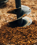 Close-up of 9 Inch Auger Bit For 3 Point Post Hole Digger With Fishtail Point HD Steel in soil, showcasing drilling action.