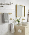 Modern bathroom with brushed gold hardware set, including towel bar with gray towel, towel ring, and toilet paper holder.