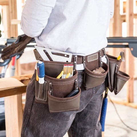 Worker wearing Heavy Duty Leather Tool Apron With Seven Pockets, Hammer Holder And Rivet Reinforced Edges For Pro Grade Toughness.