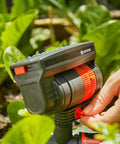 Hand adjusting ZoomMaxx Adjustable Oscillating Sprinkler on metal spike for even watering of large lawns up to 2300 sq ft.