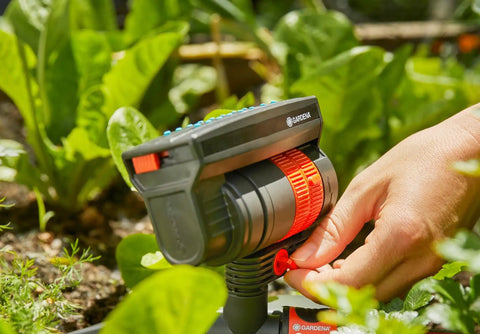 Hand adjusting ZoomMaxx Adjustable Oscillating Sprinkler on metal spike for even watering of large lawns up to 2300 sq ft.