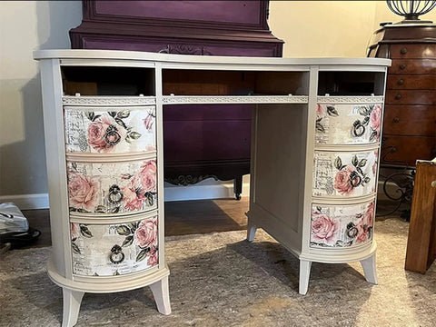 Floral vintage desk with curved drawers, featuring pink rose decals and a cream finish, set in a cozy room with vintage decor.