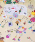 Colorful keychains and charms from 161 Piece Shrink Plastic Keychain Making Kit With 30 Sheets, Includes Hole Punch, 20 Lobster Clasps, 100 Jump Rings, 10 Lanyards for creative crafters.