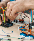 Person assembling circuit with Solderless Breadboard Jumper Wires Kit For Electronics Prototyping With 400 And 830 Tie Point Boards