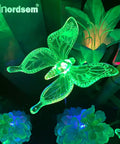 Solar Garden Lights Outdoor Set Of 6 Insect Stake Lights with green LED butterfly in garden at night, colorful atmosphere.