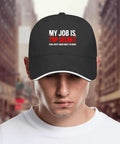 Person wearing a black hat with 'My Job Is Top Secret' text, against a blurred city street background.