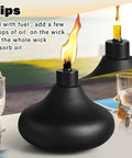 Close-up of a single black metal table top torch with flame, part of a Two Pack Metal Table Top Torches With 24.5 Ounce Citronella Fuel Capacity