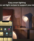 Smart lighting setup with White Ambiance 60W LED Smart Light Starter Kit on nightstand, app controls on phone screen.