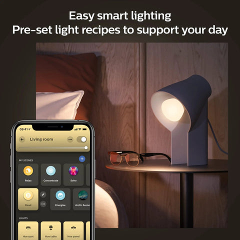 Smart lighting setup with White Ambiance 60W LED Smart Light Starter Kit on nightstand, app controls on phone screen.