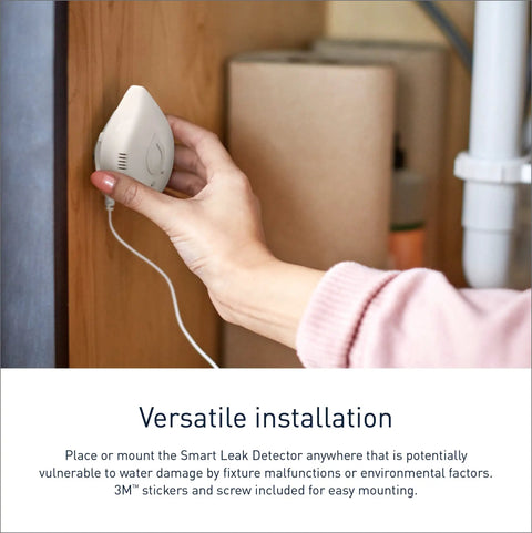 Person installing Flo Smart Water Leak Detector on wooden surface for basement monitoring