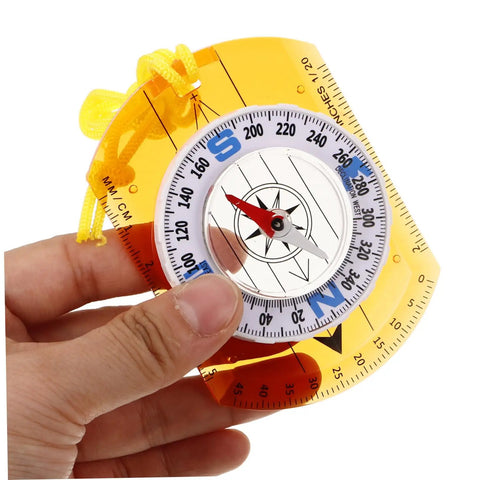Hand holding orienteering compass with luminous pointer and ruler for hiking camping and backpacking acrylic outdoor navigation tool
