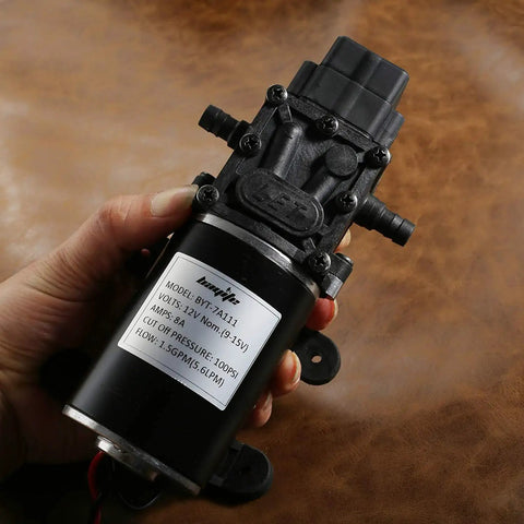 Person holding a 12V Diaphragm Water Pump 1.5 GPM At 100 PSI Self Priming DC Fresh Water Pump For RV Camper Boat Marine Lawn