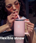 Woman sipping from a pink On The Fly 40 Oz Stainless Steel Travel Tumbler With Comfort Grip Handle And Leak Proof Straw Lid.