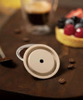 Reusable Silicone Capsule Cap For Nespresso Vertuo And VertuoLine Refills Made Easy Mess Free Compatible And Food Grade Italian Made Quality Pack Of 2 Caps Easy To Clean shown with dessert and coffee