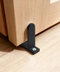 Close-up of Four Pack Universal Black Closet Door Floor Guide installed with screws for 1 3/8 inch thick sliding doors on a wooden floor.