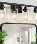 Top Shelf 4 Light Bathroom Vanity Light With Clear Glass Sleeves Matte Black Vintage Wall Sconce above mirror with plants.