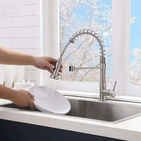 Brushed Nickel Kitchen Faucet With Pull Down Sprayer used for rinsing dishware in modern kitchen setting.