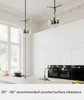 Two Sacha Pendant Light In Natural Iron Finish With Clear Glass Shade over modern kitchen island, showcasing suggested clearance.